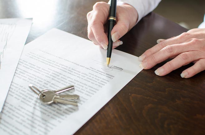 Woman signing a real estate contract on a desk
